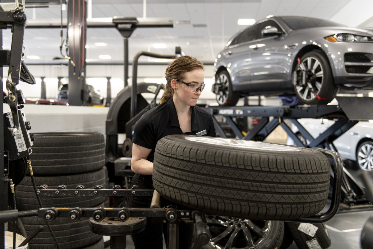 An automotive technician at Frisco Land Rover Jaguar works on a tire